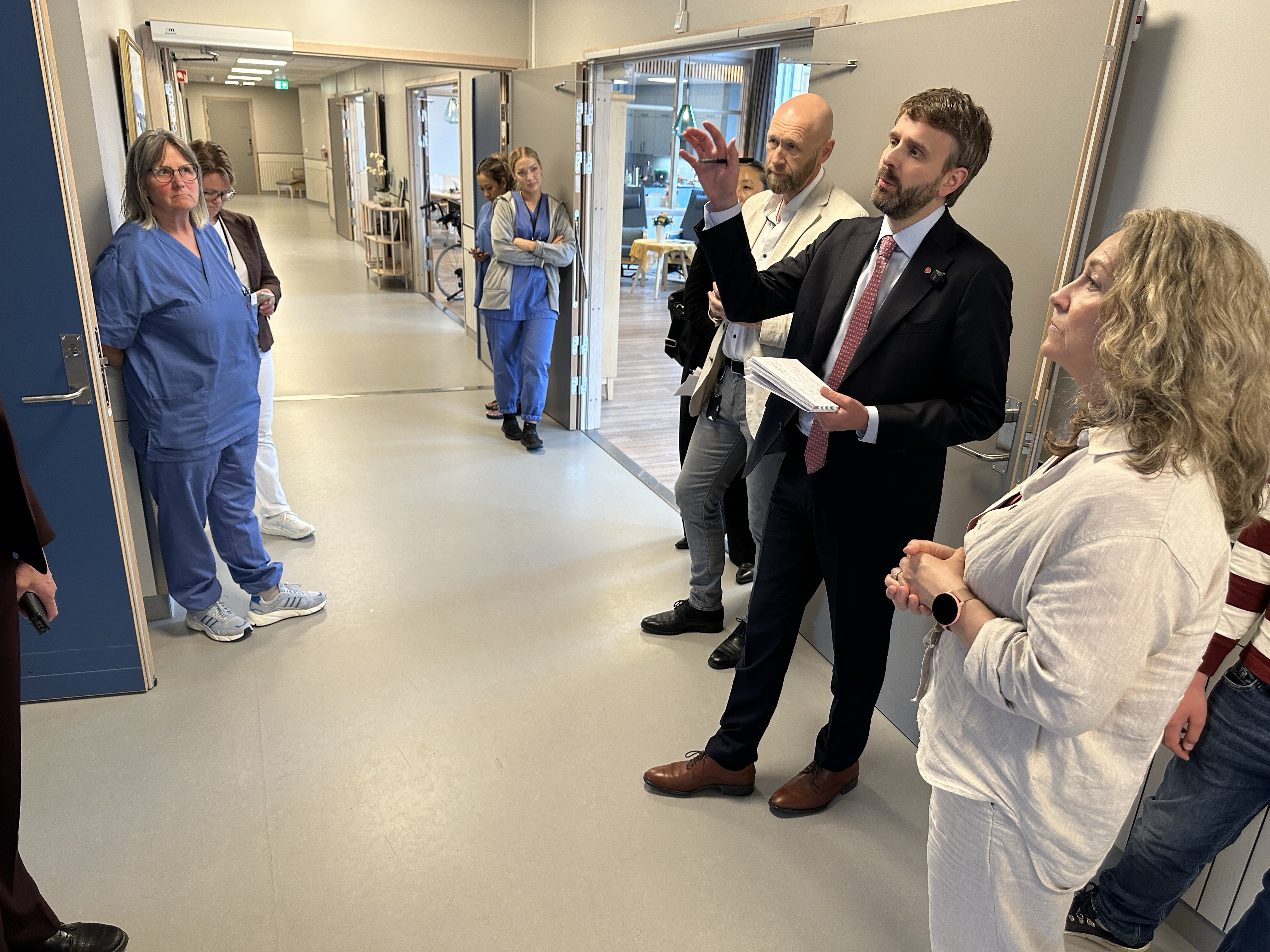 Bildet viser statsr&aring;den i korridoren p&aring; Heradsbygda omsorgssenter. Han prater og st&aring;r sammen med kommunedirekt&oslash;ren og ordf&oslash;reren, i tillegg til en del ansatte p&aring; omsorgssenteret.