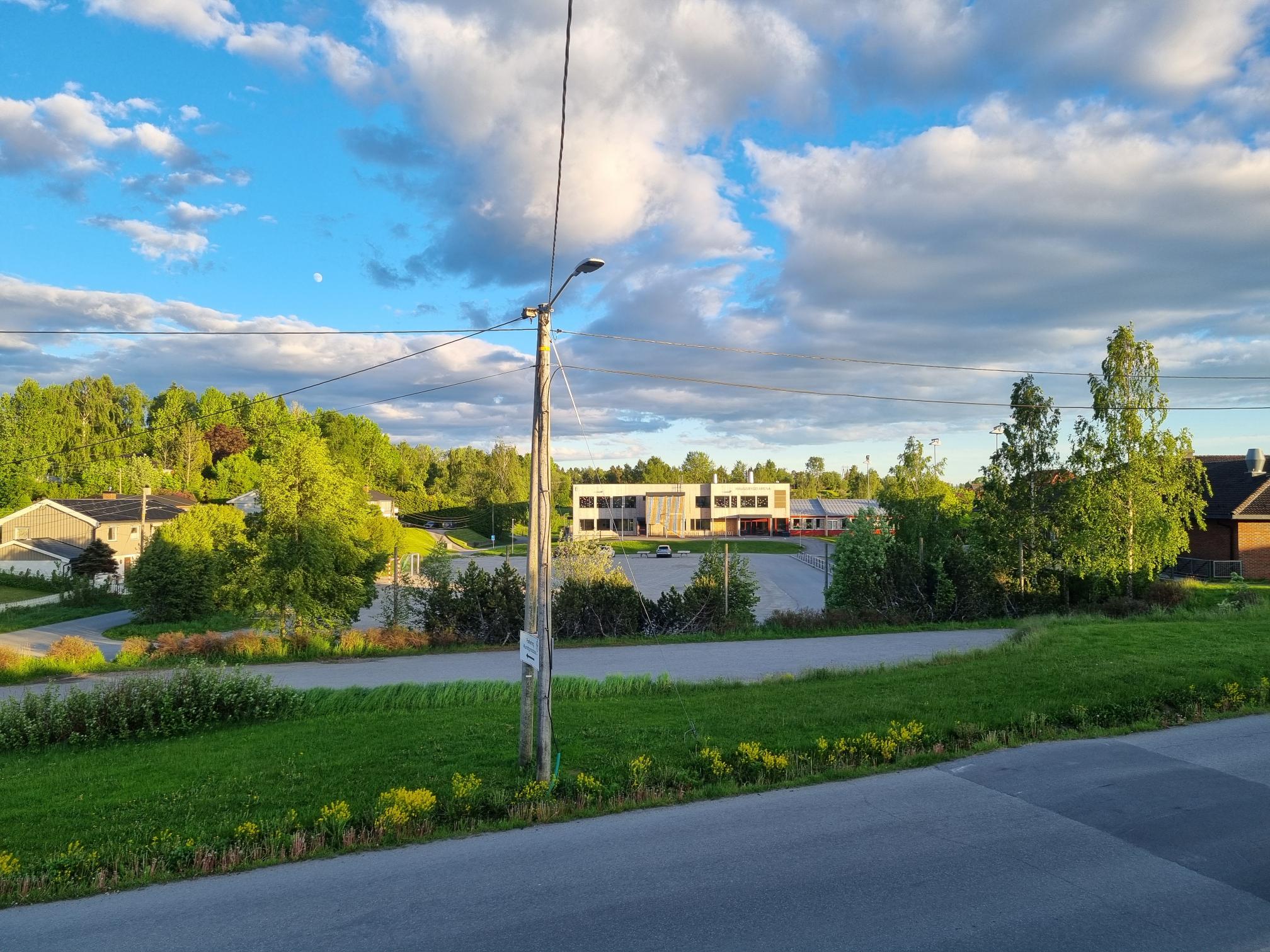 Bildet viser Haugsbygd ungdomsskole i kveldssol retning dagens grusbane