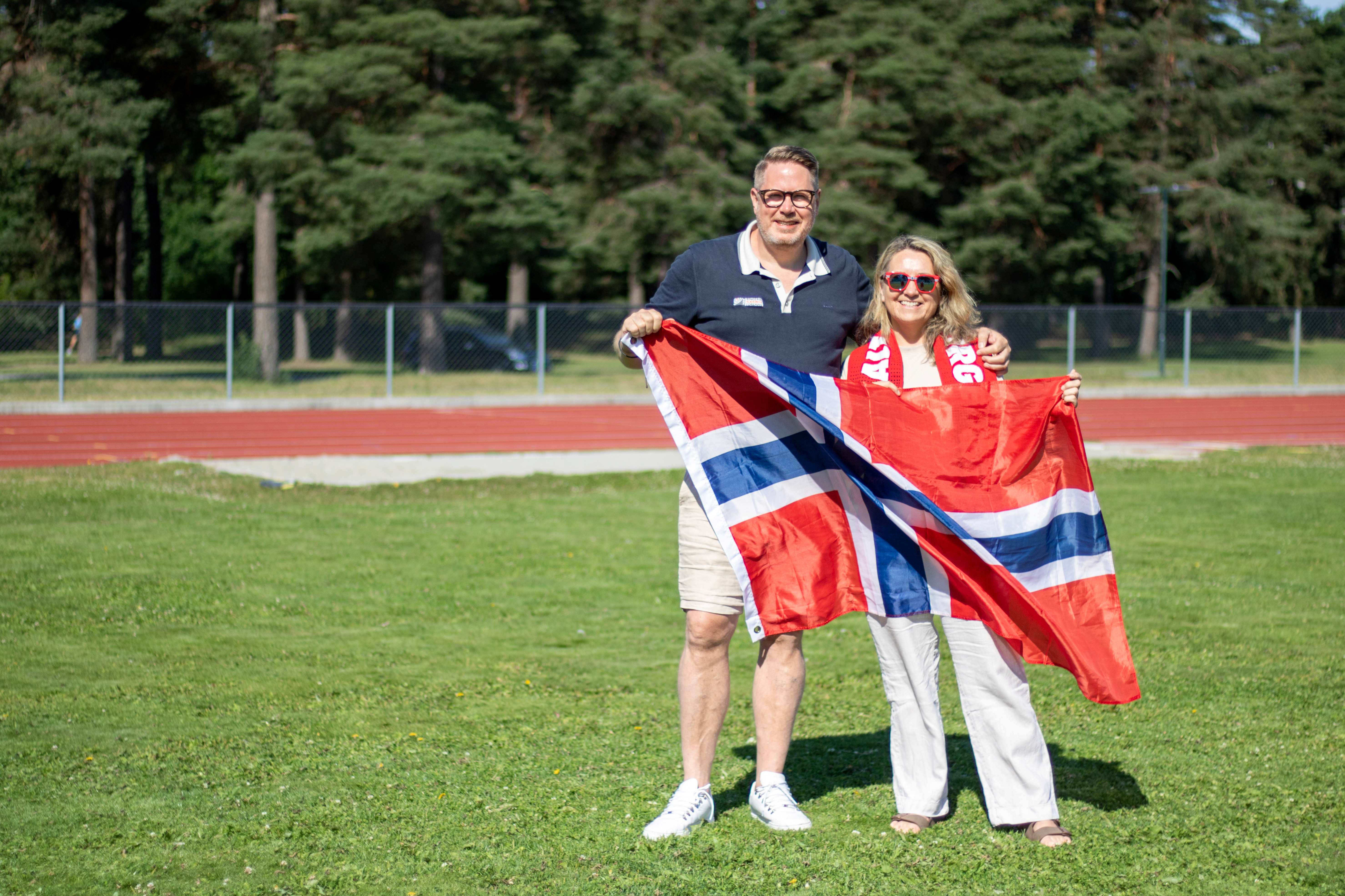 Bildet viser ordfører og leder for RNF på fotballbanen med et stort norsk flagg.