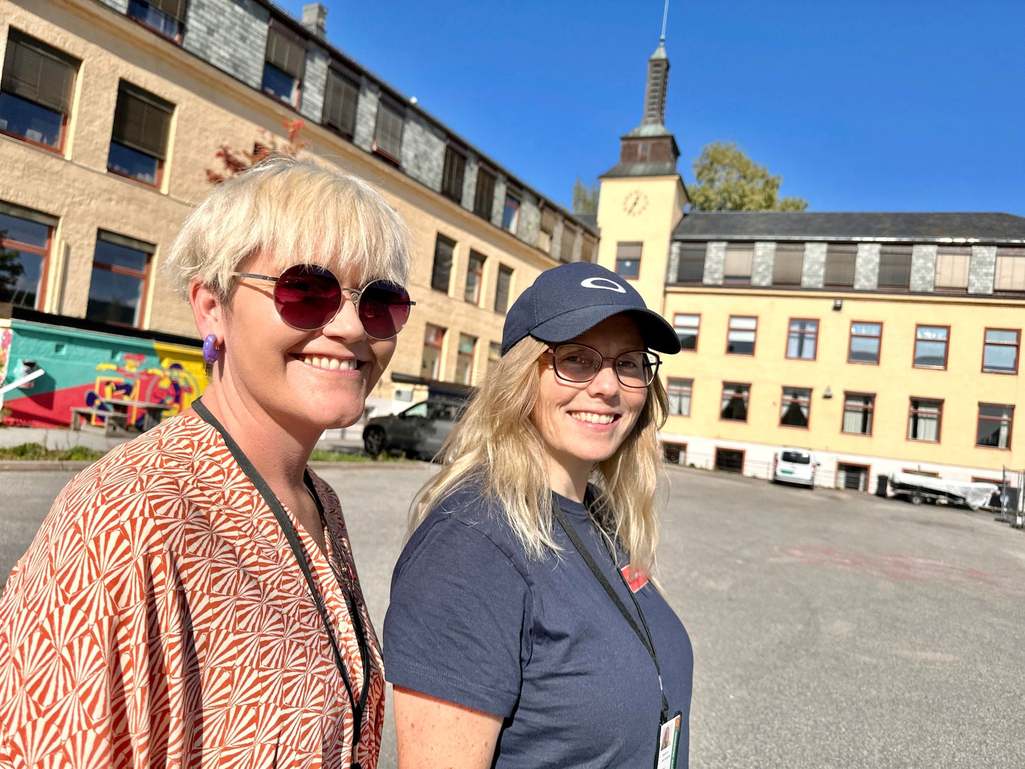 Bildet viser Reni Karoline Odden og Ellen Margrethe Stabursvik som inviterer til dugnad. De står foran Hønefoss gamle skole.